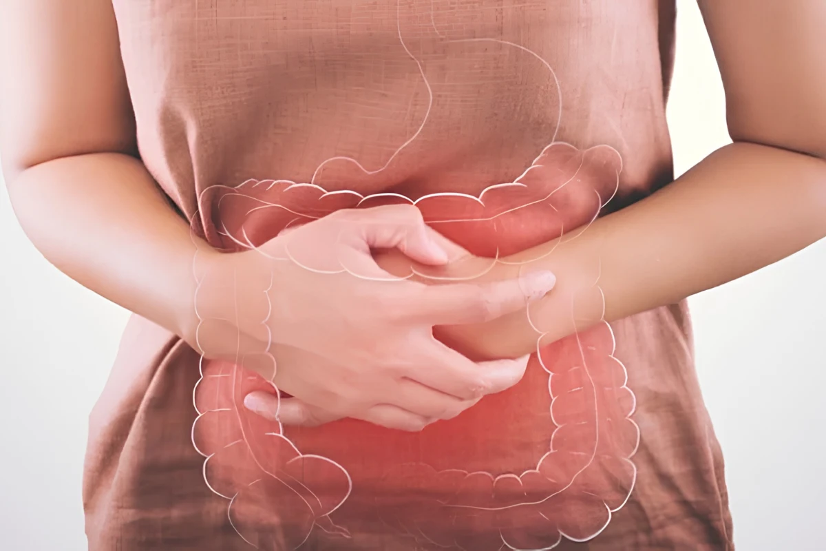 A person holding their midsection with a transparent line-art overlay of the stomach and large intestine to signify chronic bloating, abdominal pain, or digestive discomfort.