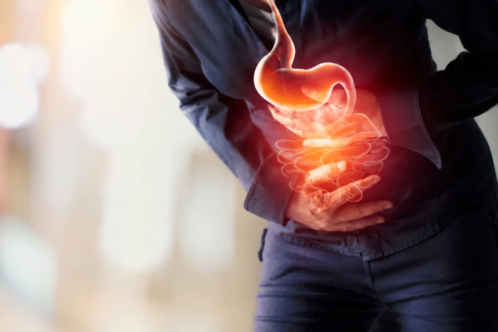 Why Colon Cancer Is Rising in People Under 50 in the UAE 2 A person holding their abdomen with a glowing overlay illustrating the stomach and intestines to represent abdominal pain or digestive discomfort.
